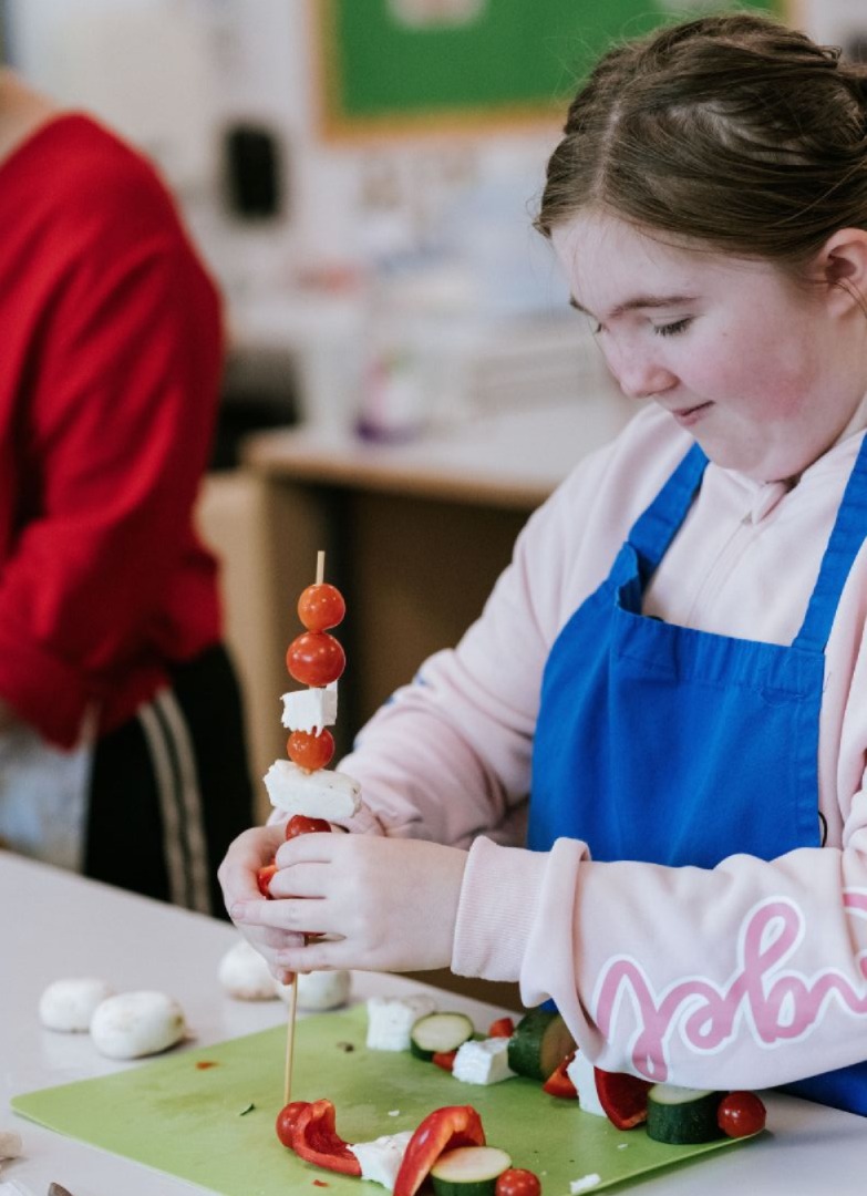 Female student making vegetable kebabs in cookery